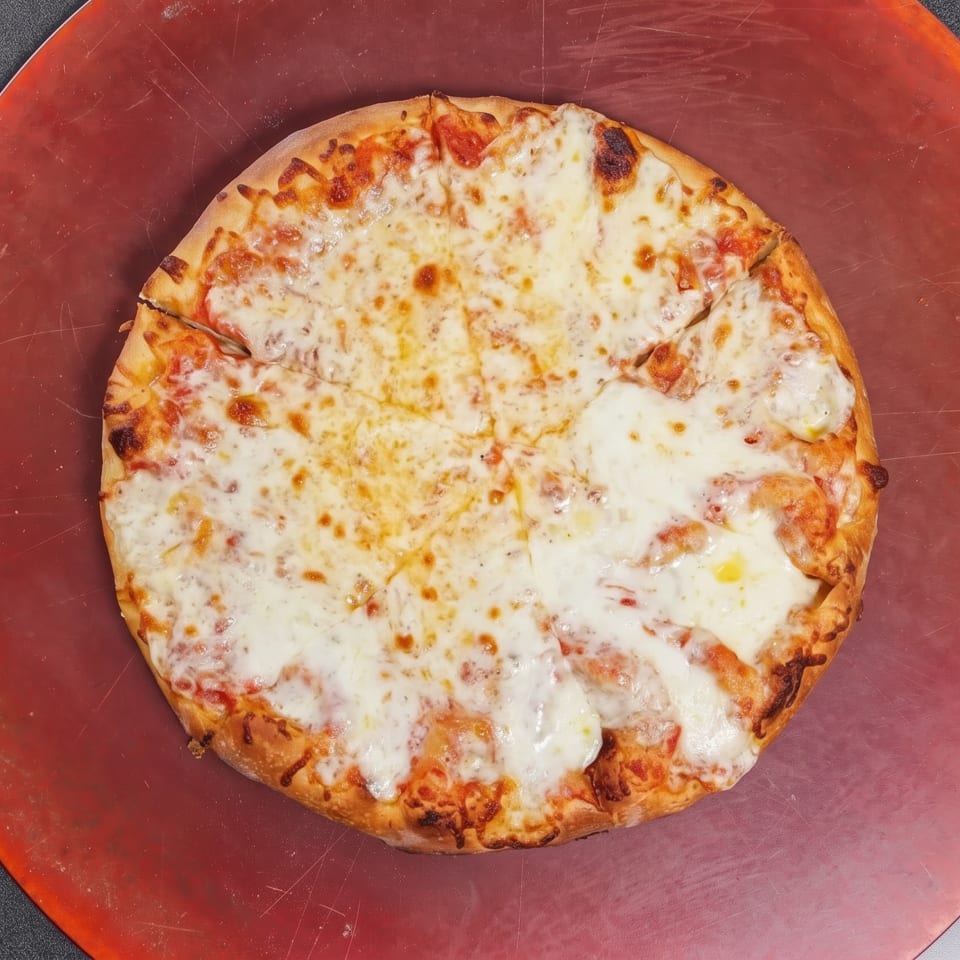 Cheese-covered pizza rests on a red serving board, with a golden-brown crust and visible tomato sauce beneath melted cheese.